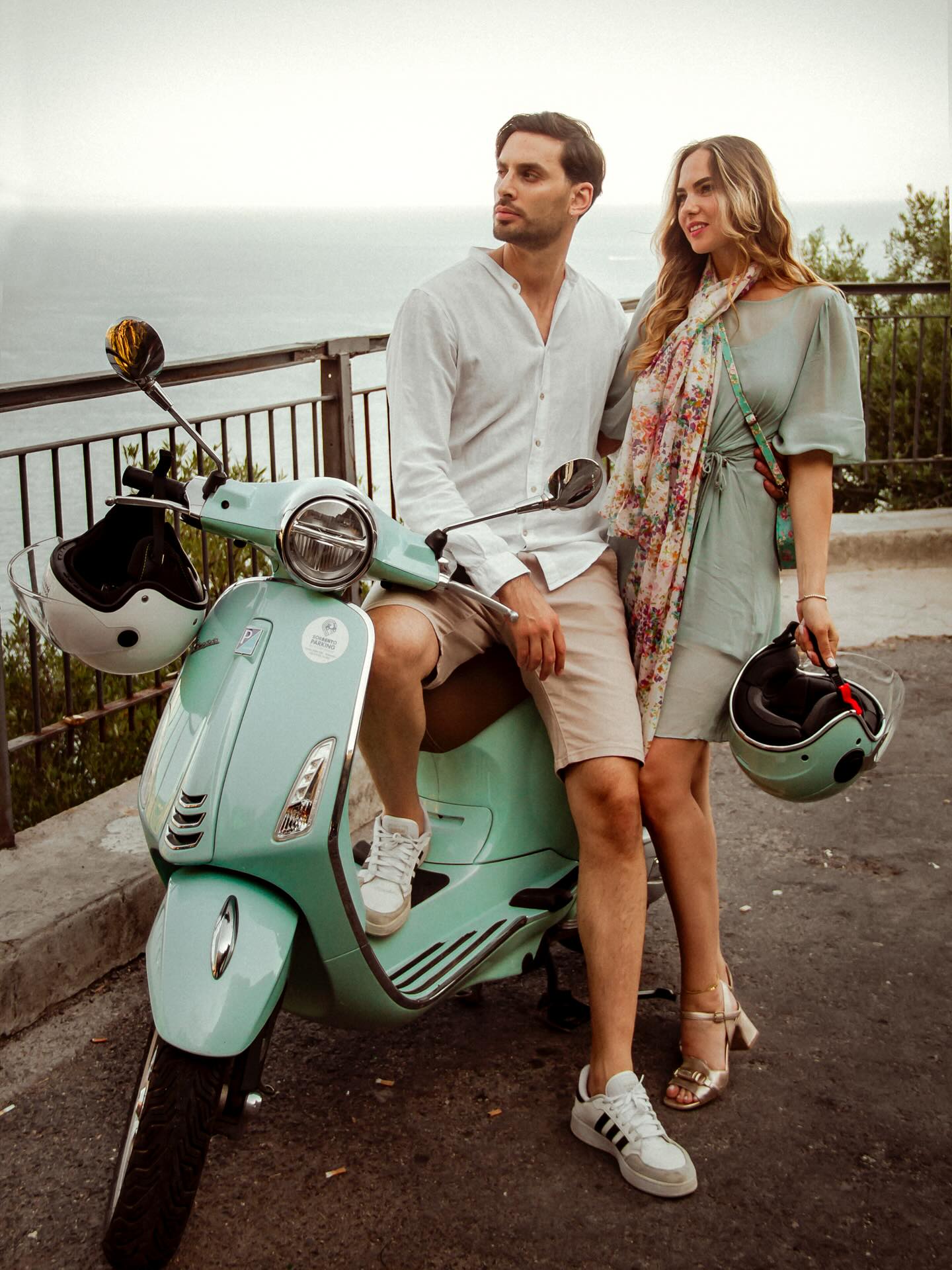 couple standing with a green vespa